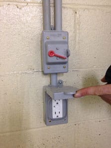 Hand holding door open to waterproof outdoor outlet protector