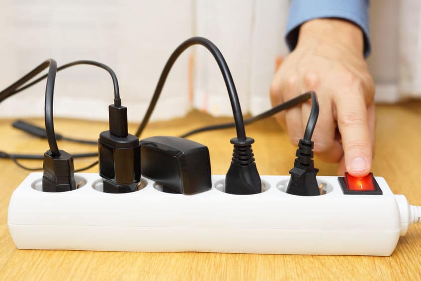 Hand turning off a power bar with 5 electrical plugs