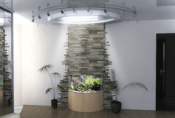 An aquarium built into a stone wall feature in a contemporary room with wooden flooring and premium electric track lighting installed on the ceiling. Two potted plants are elegantly positioned on either side of the aquarium, enhancing the sophisticated ambiance.